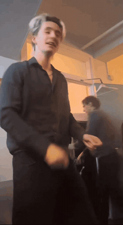 A Man In A Black Shirt Is Dancing In A Room With Other People GIF