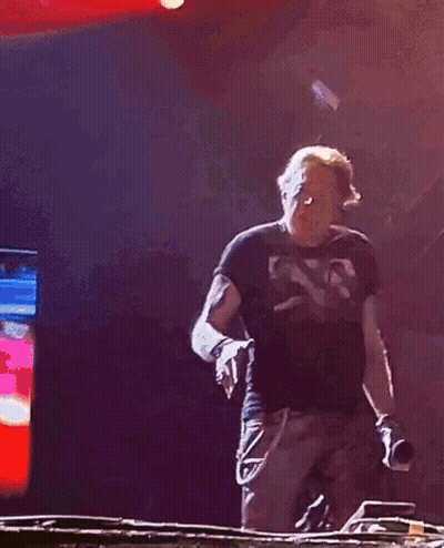 A Man In A Black Shirt Is Dancing In Front Of A Red Light GIF