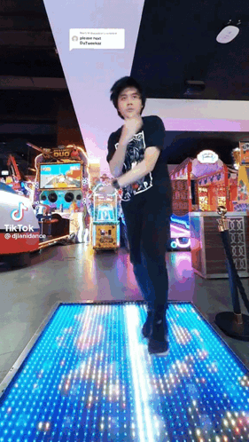 A Man In A Black Shirt Is Dancing On A Lighted Floor In An Amusement Park .. GIF
