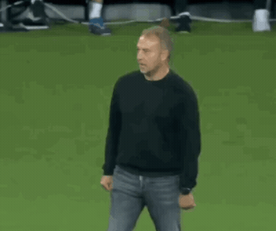 A Man In A Black Shirt Is Dancing On A Soccer Field . GIF