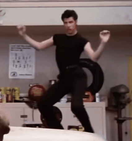 A Man In A Black Shirt Is Dancing With A Tire Around His Waist In A Kitchen GIF