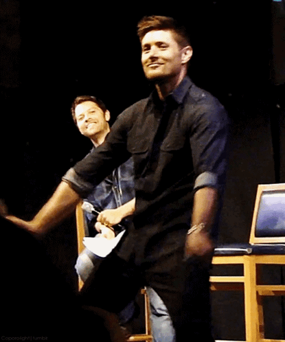 A Man In A Black Shirt Is Dancing With Another Man In A Blue Shirt GIF