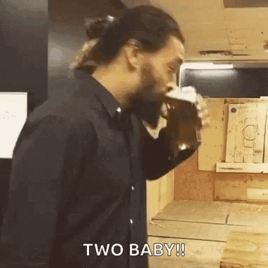 A Man In A Black Shirt Is Drinking A Beer From A Glass . GIF
