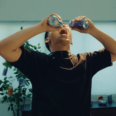 A Man In A Black Shirt Is Drinking From Two Cans With His Mouth Open GIF
