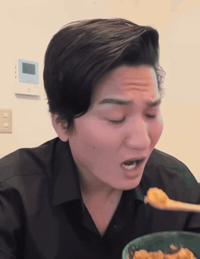 A Man In A Black Shirt Is Eating A Bowl Of Food With A Spoon GIF
