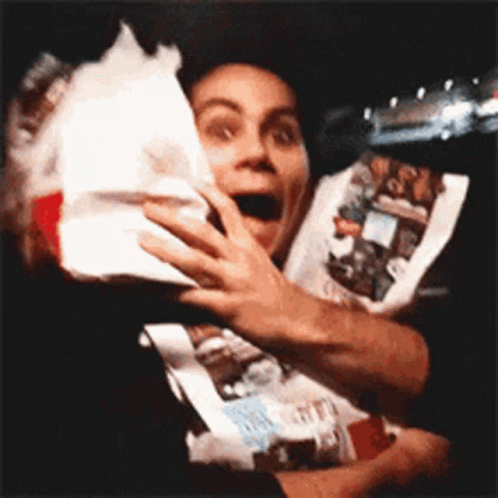 A Man In A Black Shirt Is Holding A Bag Of Food . GIF