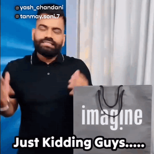 A Man In A Black Shirt Is Holding A Bag That Says Imagine GIF