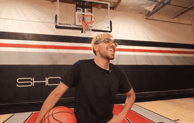 A Man In A Black Shirt Is Holding A Basketball In Front Of A Wall That Says Sho GIF