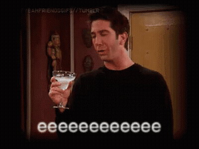 A Man In A Black Shirt Is Holding A Martini Glass . GIF
