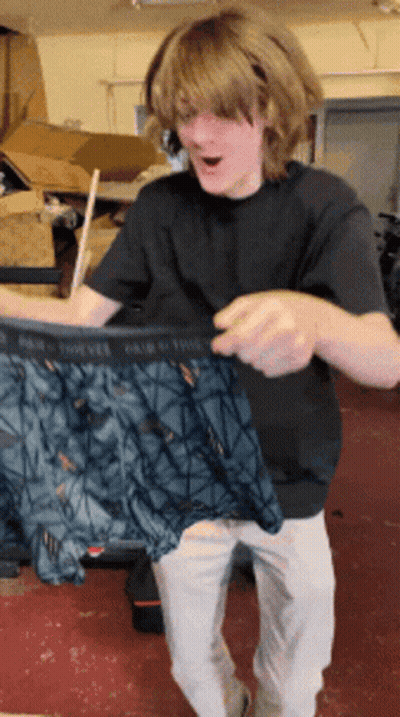 A Man In A Black Shirt Is Holding A Pair Of Underwear That Says Pair Of Twelve GIF