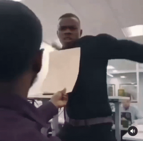 A Man In A Black Shirt Is Holding A Piece Of Paper In Front Of His Face GIF
