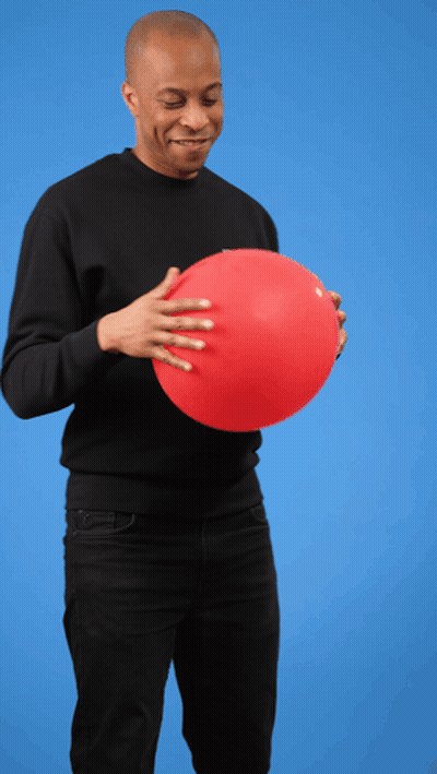 A Man In A Black Shirt Is Holding A Red Balloon In His Hands GIF