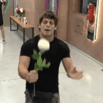 A Man In A Black Shirt Is Holding A Rose In His Hands . GIF