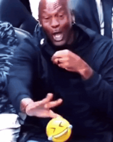 A Man In A Black Shirt Is Holding A Yellow Ball With A Smiling Face On It GIF
