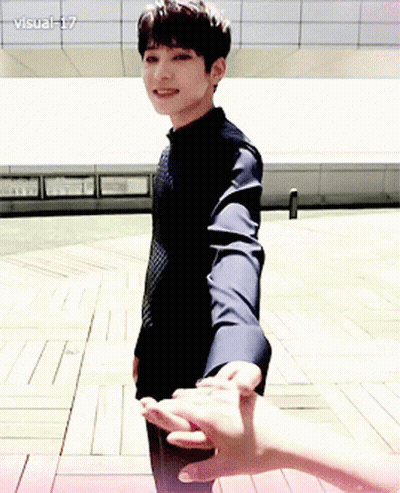 A Man In A Black Shirt Is Holding Another Man 'S Hand While Standing On A Wooden Floor .. GIF