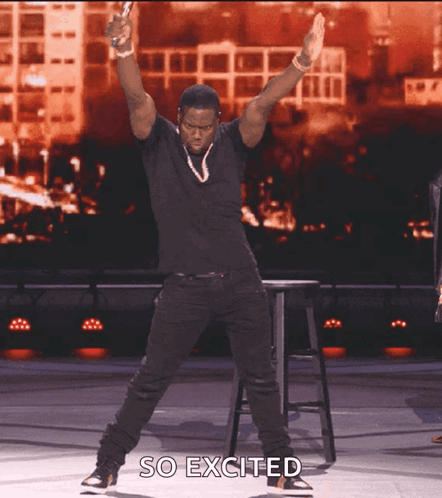 A Man In A Black Shirt Is Jumping In The Air With The Words So Excited Above Him GIF
