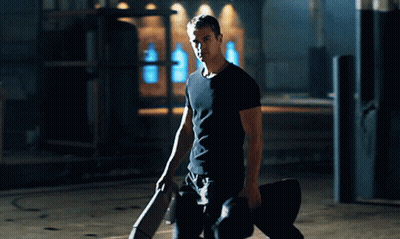 A Man In A Black Shirt Is Kneeling Down Holding A Skateboard GIF