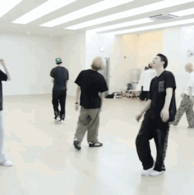 A Man In A Black Shirt Is Kneeling On The Floor In A Dance Studio GIF