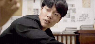 A Man In A Black Shirt Is Looking At The Camera With A Serious Look On His Face GIF