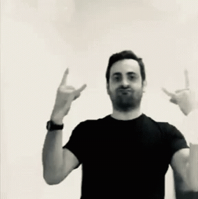 A Man In A Black Shirt Is Making A Devil Horns Sign GIF