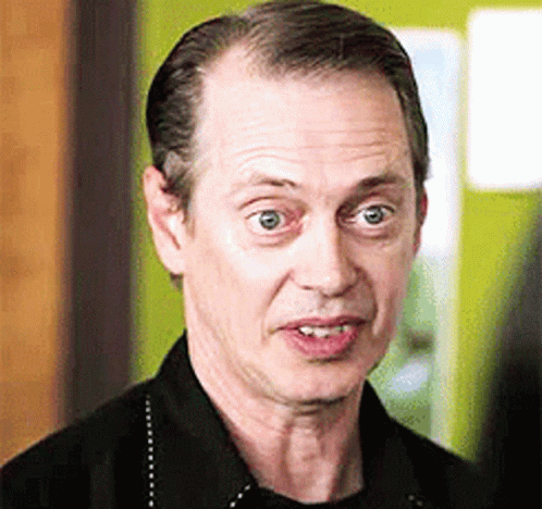 A Man In A Black Shirt Is Making A Funny Face And Looking At The Camera . GIF
