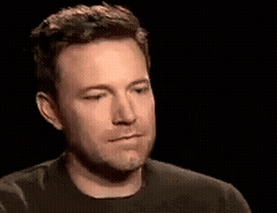 A Man In A Black Shirt Is Making A Funny Face In A Dark Room . GIF