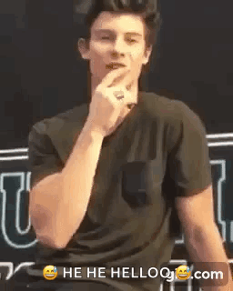 A Man In A Black Shirt Is Making A Funny Face With His Hand . GIF