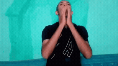 A Man In A Black Shirt Is Making A Funny Face With His Hands Together . GIF