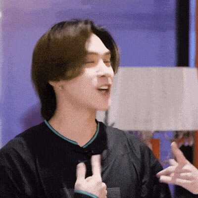 A Man In A Black Shirt Is Making A Peace Sign With His Hands GIF