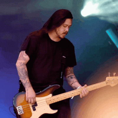 A Man In A Black Shirt Is Playing A Bass Guitar With A Blue Background GIF