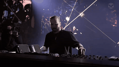 A Man In A Black Shirt Is Playing A Dj Set With A Camera Behind Him GIF