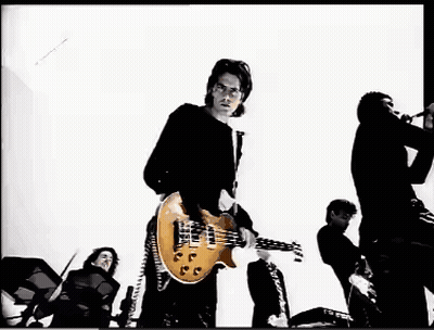 A Man In A Black Shirt Is Playing A Guitar In A Black And White Photo GIF