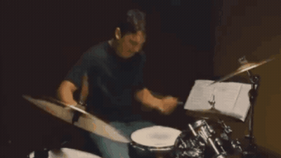 A Man In A Black Shirt Is Playing Drums GIF