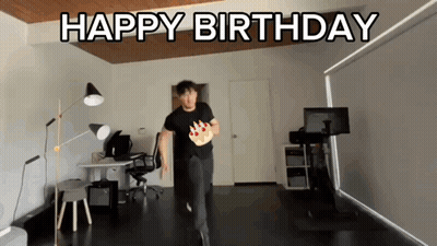 a man in a black shirt is running with a birthday cake in his hand and the words happy birthday behind him
