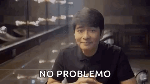 A Man In A Black Shirt Is Sitting At A Table With His Hands Folded And Says `` No Problemo '' . GIF