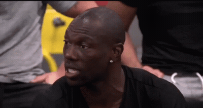 A Man In A Black Shirt Is Sitting In A Gym With A Group Of People Behind Him . GIF