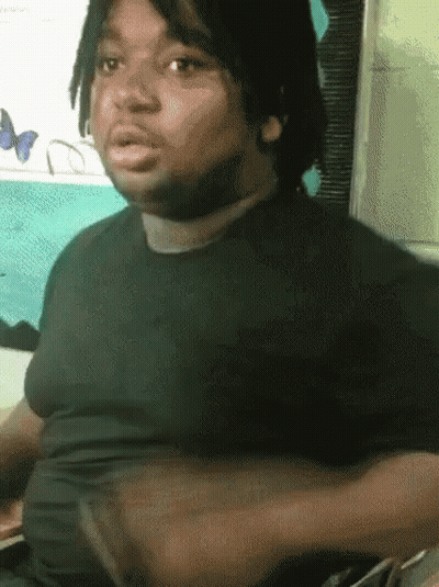 A Man In A Black Shirt Is Sitting In Front Of A Butterfly Wall GIF