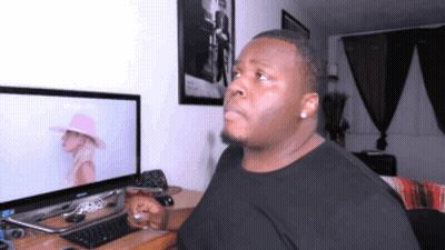 A Man In A Black Shirt Is Sitting In Front Of A Computer GIF