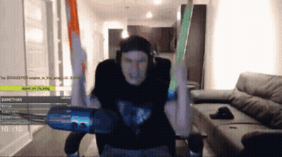 A Man In A Black Shirt Is Sitting In Front Of A Microphone With His Arms In The Air . GIF