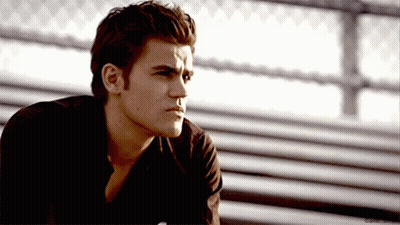 A Man In A Black Shirt Is Sitting On A Bench With His Eyes Closed . GIF
