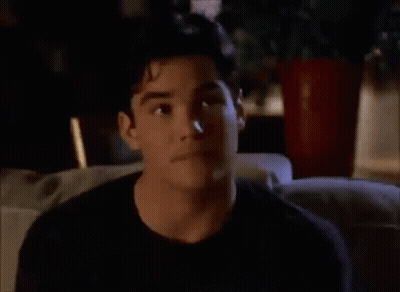 A Man In A Black Shirt Is Sitting On A Couch Looking At Something GIF