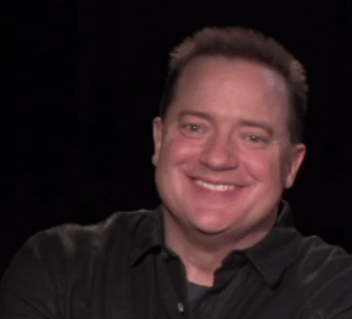 A Man In A Black Shirt Is Smiling With The Words Look At Behind Him GIF