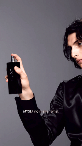 A Man In A Black Shirt Is Spraying A Bottle Of Perfume GIF