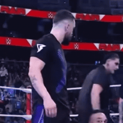 A Man In A Black Shirt Is Standing In A Boxing Ring With Another Man . GIF