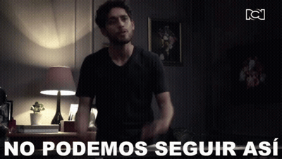 A Man In A Black Shirt Is Standing In A Dark Room With The Words " No Podemos Seguir Así " Behind Him GIF