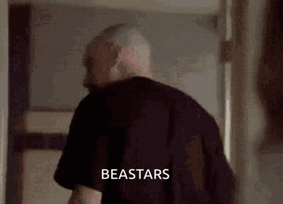 A Man In A Black Shirt Is Standing In A Hallway With The Word Beastars Written On The Bottom Of The Image . GIF