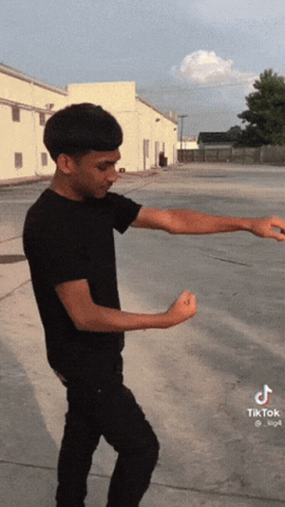 A Man In A Black Shirt Is Standing In A Parking Lot With His Arms Outstretched And A Tiktok Logo On The Bottom Left GIF
