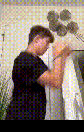 A Man In A Black Shirt Is Standing In A Room GIF