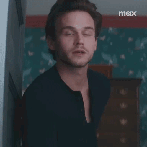 A Man In A Black Shirt Is Standing In A Room With The Words `` Excuse Me '' Written On His Face . GIF