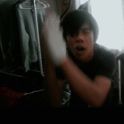 A Man In A Black Shirt Is Standing In Front Of A Closet GIF